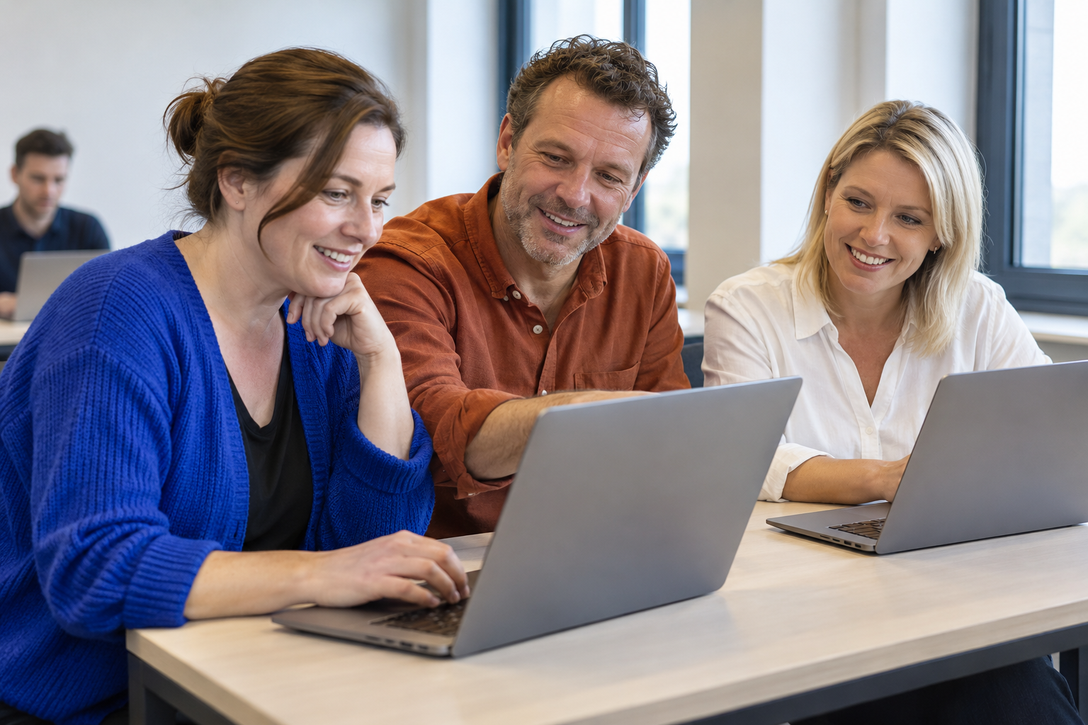 Drie deelnemers oefenen samen met laptops tijdens een opleiding (AI-sfeerbeeld)