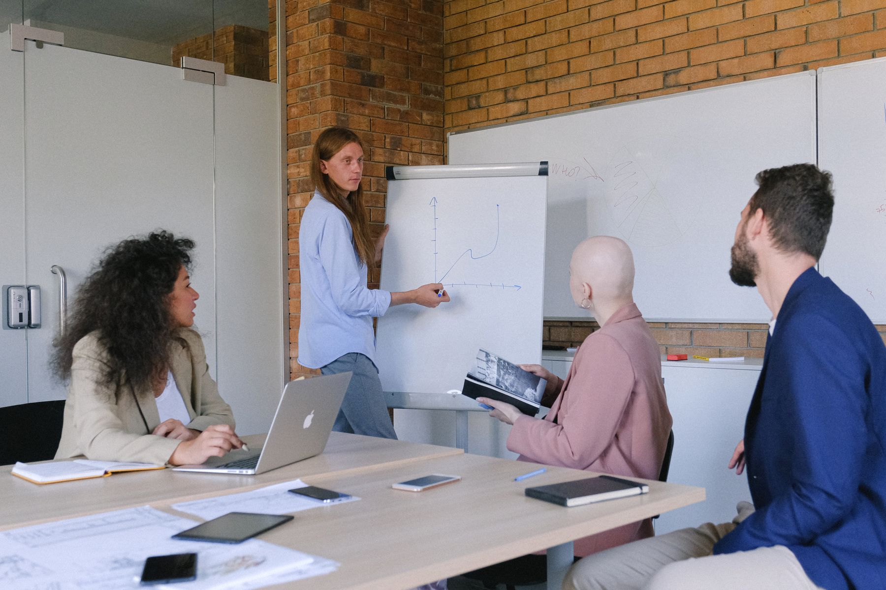 Een trainer bespreekt een oefening met deelnemers rond de werktafel