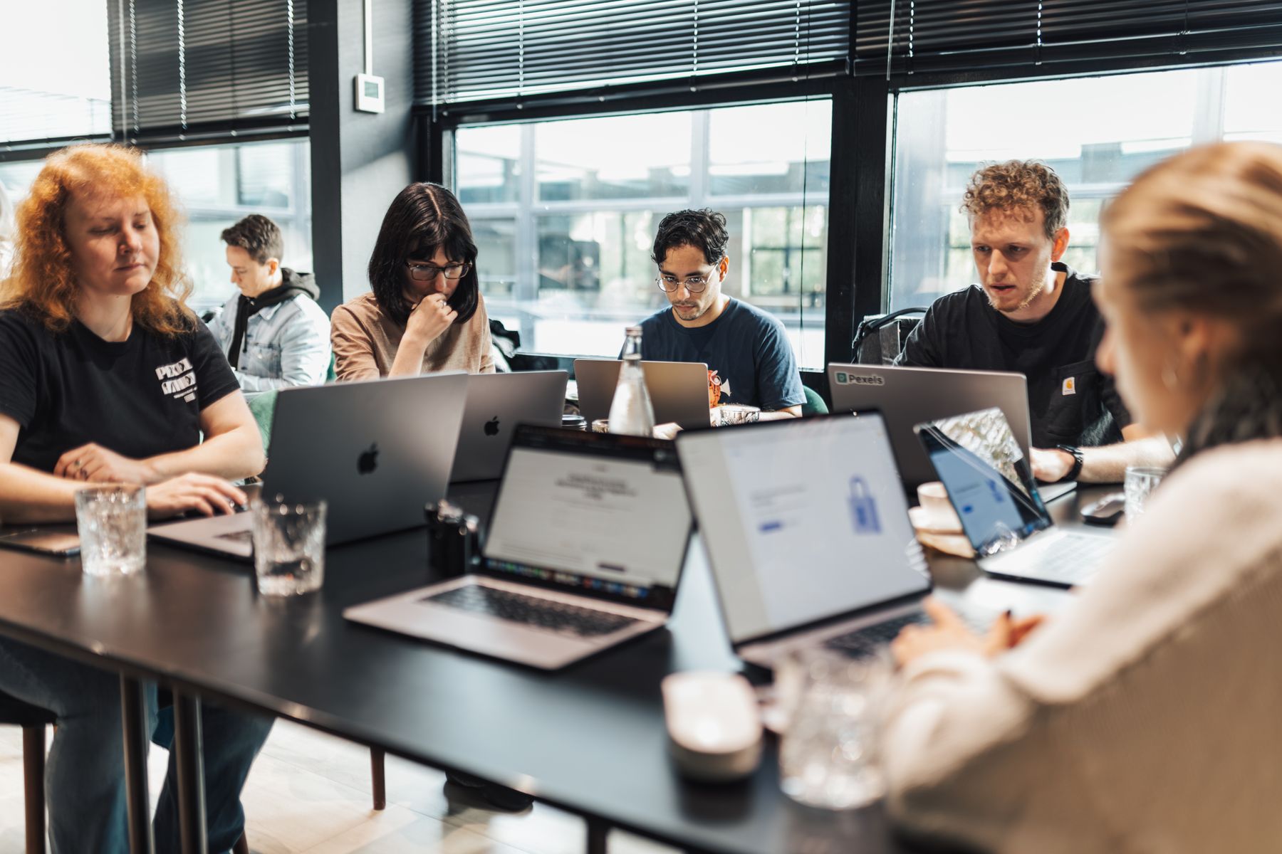 Een kleine groep deelnemers werkt met laptops rond een vergadertafel