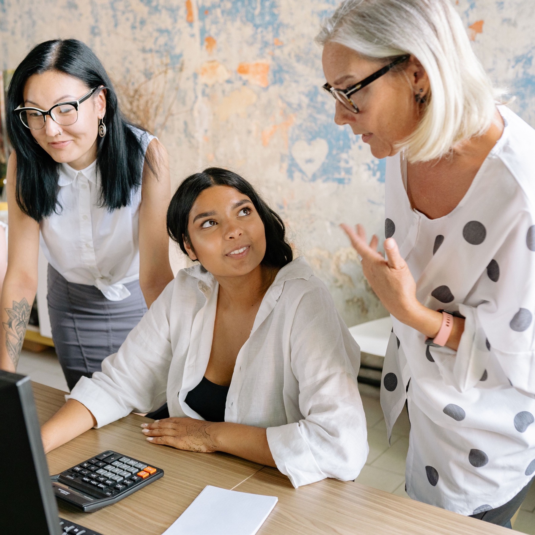 Drie collega's bespreken samen een opdracht aan een tafel met een computer