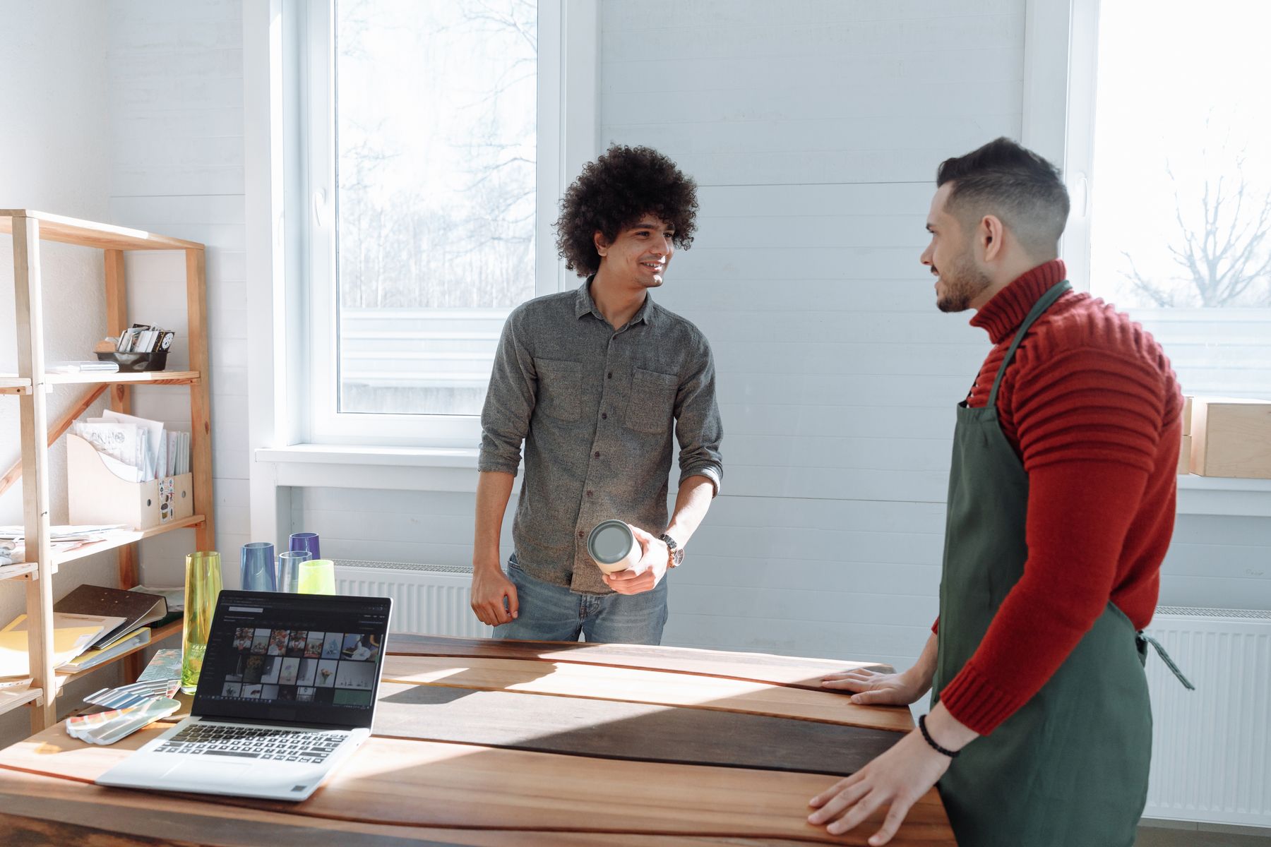 Een ondernemer en een medewerker bespreken hun werk aan een tafel met een laptop